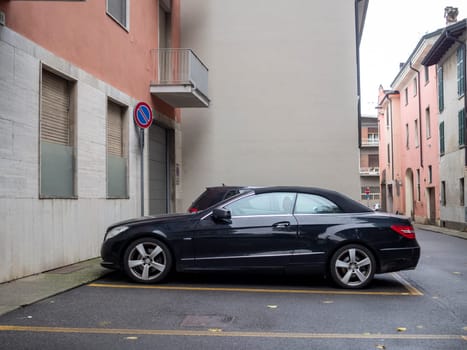 Cremona, Lombardy, Italy October 15th 2024 Parked black mercedes convertible on a narrow residential street in an italian town, showcasing urban life