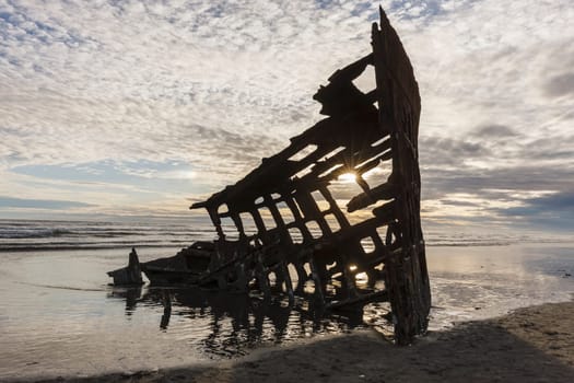 The skeleton of the Peter Iredale shipwreck at sunset in Oregon.