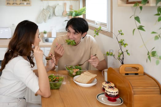 Happy young couple enjoying a healthy meal together in a minimalist kitchen.