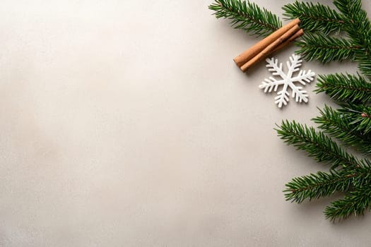 Fresh pine branches, cinnamon sticks, and snowflake ornament create cozy winter vibe.