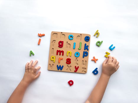 Colorful alphabet puzzle with childrens hands learning letters.