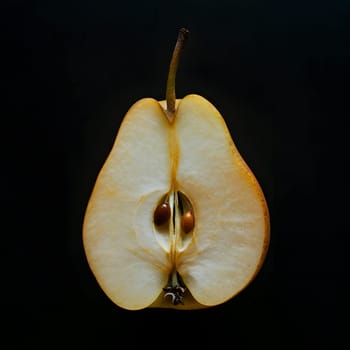 A halved pear showcasing seeds and inner texture against a black backdrop