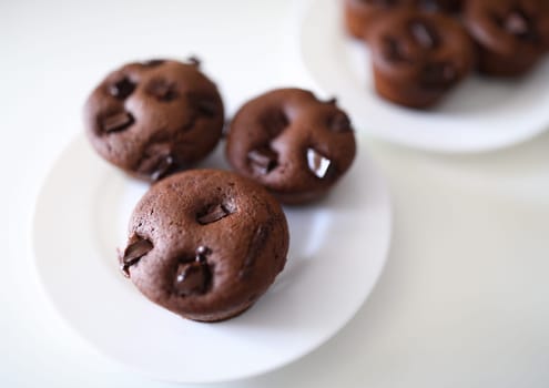 Close-up of delicious chocolate muffins with crispy top served on white plate. Homemade tasty cupcakes with cocoa stuffing. Yummy dessert and sweets concept