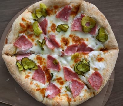 Top view of delicious pizza. Traditional italian meal. Round shaped snack with salami double cheese sauce and pickles. Tasty lunch. Unhealthy food concept