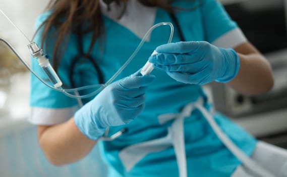 Close-up of female hands in sterile gloves putting dropper to sick patient. First aid procedures. Giving medical care. Healthcare and prevention concept