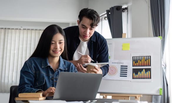 Young businesswoman explains work plan in meeting to teammates in conference room..