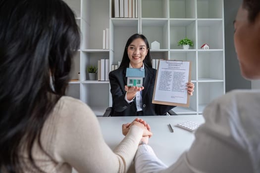 The real estate agent makes an offer to get the couple to sign a contract to buy the house. Happy male and female married customers make intimate deals with agents. real estate concept..