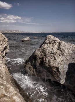 Seascape with a view of the rocky coast, beautiful sea surface, waves crashing on a rocky cliff. A clear sunny day.