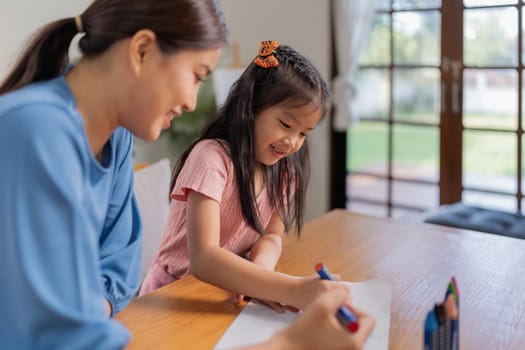 Happy family mother and daughter study or draw together at home in living room.