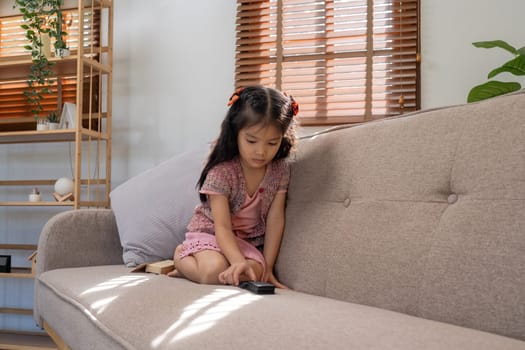 Asian little girl sitting on sofa at home.