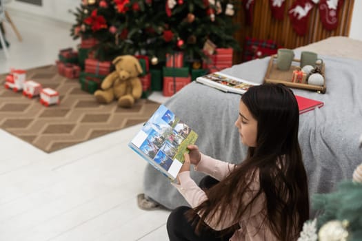 A teenage girl looks at a photo book at Christmas.