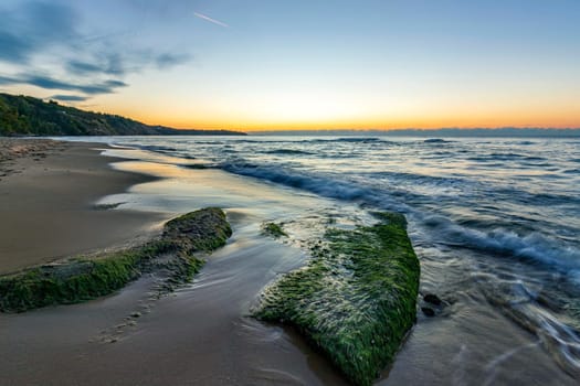 Seascape view with rocks with moss, before sunrise