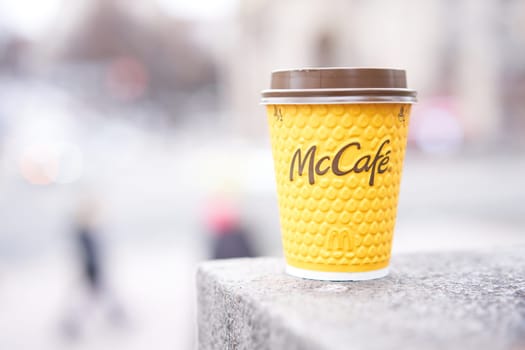 Ukraine, Kiev February 2021 yellow paper cup with coffee McCafe in hand McDonalds take away coffee