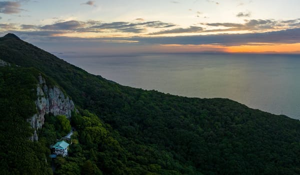 Aerial panoramic view of remote temple on mountain by sea at sunrise. High quality photo