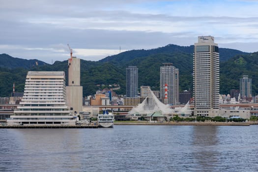 Kobe, Japan - September 23, 2023: Hotel and tower buildings on city waterfront by Mt. Rokko. High quality photo