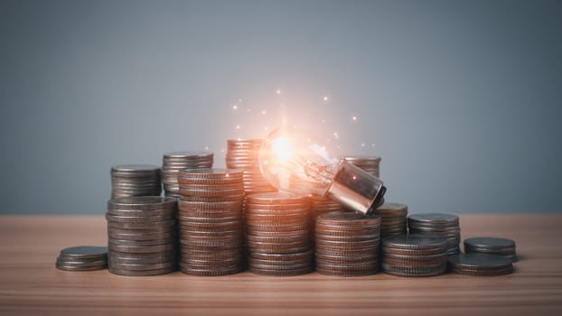 Bright light bulbs and coins lined up on wooden floor on a white background. Financial plan or business. Concepts of finance, savings and investment. Planning money management for success in the future