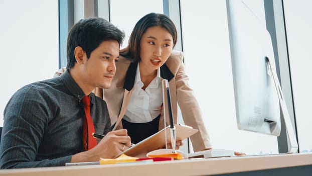 Two business people talk project strategy at office meeting room. Businessman discuss project planning with colleague at modern workplace while having conversation and advice on financial report. Jivy