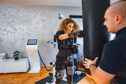 A woman activates muscle stimulation while training with a coach.