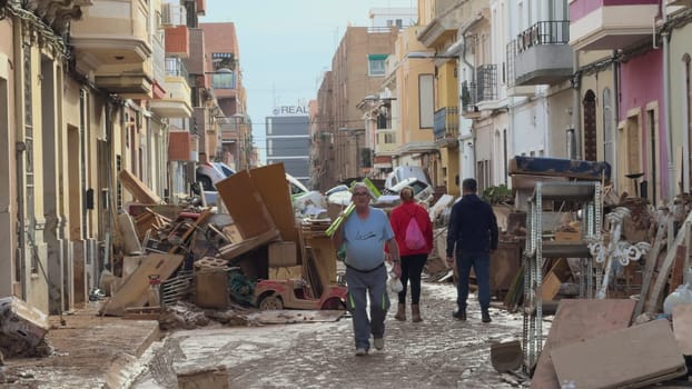 On November 2, 2024, citizens in Benetússer, Valencia face muddy streets and wrecked cars after DANA floods, displaying both devastation and resilience
