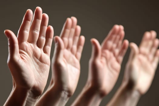 A group of people are holding their hands up in a prayerful gesture. Concept of unity and togetherness, as the people are all reaching out to each other in a shared moment of faith