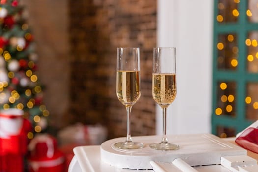 New year time party in home interior with christmas tree. Two empty champagne glass and desk