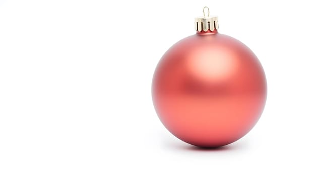 A single red Christmas ornament isolated on a white background, reflecting light and showcasing intricate details. Perfect for festive designs and holiday themes