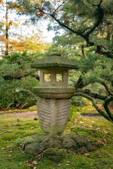 A tranquil Japanese stone lantern stands amidst lush greenery and moss, creating a calming garden atmosphere. Perfect for themes of tranquility, nature, and traditional Japanese aesthetics.