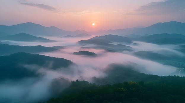 A breathtaking aerial view of a foggy mountain range at sunset with clouds hanging low in the sky, creating a mystical atmosphere. The water reflects the afterglow of dusk on the horizon