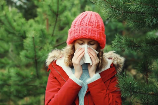 Sick exhausted woman sneezing blow nose using tissue, unhealthy suffering girl feels unwell outdoors in winter park