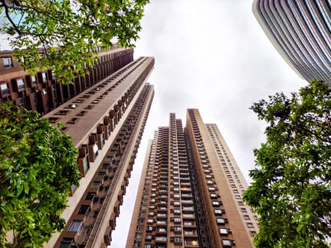 Towers dominate the skyline with a mix of modern and classic architecture under a cloudy sky.