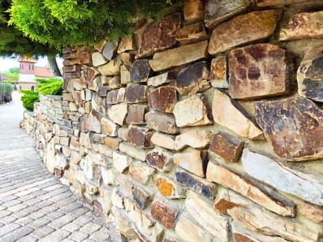 The stone wall lines a pathway, complemented by lush greenery, creating a peaceful atmosphere for leisurely walks.