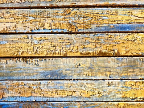 The surface features rough, peeling paint in shades of blue and yellow, ideal for artistic backgrounds and textured elements.