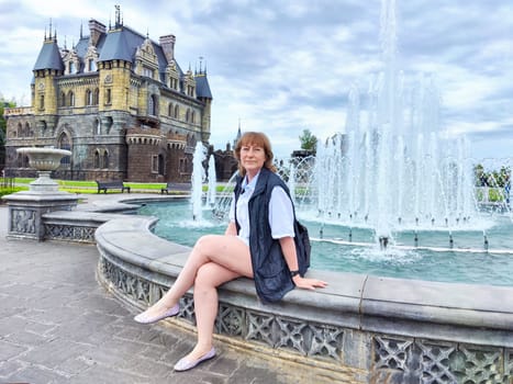 A woman enjoys her travel adventure at Garibaldi Castle, showcasing her excitement in a historic setting. The adventures of a middle-aged female tourist on a trip