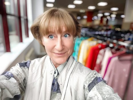 A middle-aged woman with unique style enjoys shopping in a vibrant store surrounded by various clothing items.