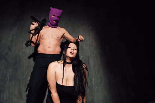 Strong man and woman in black lingerie on dark background with guns