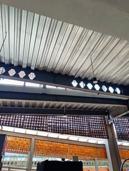 A detailed view of an industrial ceiling featuring intricate brick patterns and a modern pendant light. The design combines steel beams and woven textures for an urban architectural look.