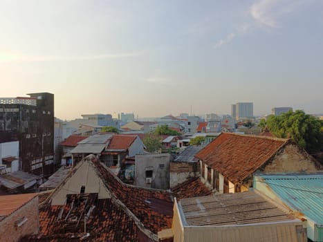 An aerial perspective showcasing the variety of roofing styles in a densely populated urban area under a clear blue sky, highlighting architectural diversity and city life.