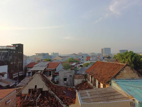 An aerial perspective showcasing the variety of roofing styles in a densely populated urban area under a clear blue sky, highlighting architectural diversity and city life.