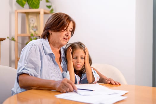 Depressed granddaughter and concerned grandmother review financial bills together, sharing tense and emotional moment as they face financial challenges at home