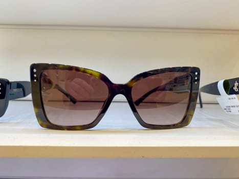 Cremona, Lombardy, Italy October 15th 2024 Brown tortoiseshell sunglasses with silver studs sit on a white shelf, embodying current eyewear trends