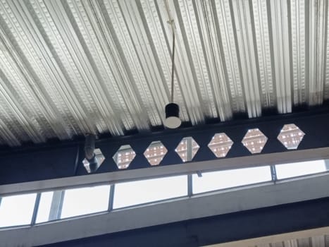 A detailed view of an industrial ceiling featuring intricate brick patterns and a modern pendant light. The design combines steel beams and woven textures for an urban architectural look.