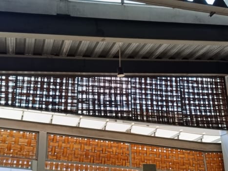 A detailed view of an industrial ceiling featuring intricate brick patterns and a modern pendant light. The design combines steel beams and woven textures for an urban architectural look.