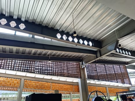 A detailed view of an industrial ceiling featuring intricate brick patterns and a modern pendant light. The design combines steel beams and woven textures for an urban architectural look.