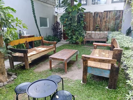 A charming garden area with rustic wooden benches and a table surrounded by lush greenery, creating a peaceful and inviting outdoor space.