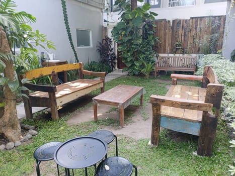 A charming garden area with rustic wooden benches and a table surrounded by lush greenery, creating a peaceful and inviting outdoor space.