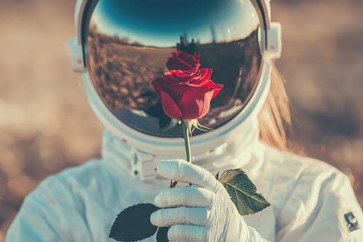 Astronaut holding red rose with reflective helmet.