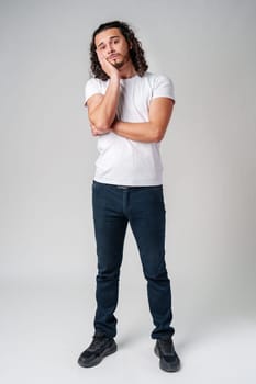 A young man stands thoughtfully against a plain background, expressing contemplation close up