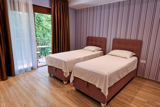 Two single beds in a hotel room near a panoramic window. High quality photo