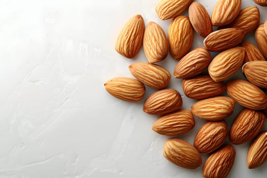 A mound of almonds, a type of nut, sits on a clean white surface. Almonds are a nutritious food ingredient often used in cuisine and produce a versatile nut for cooking