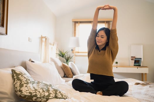 Carefree young woman stretching on bed and preparing for the day.